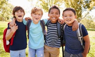 A group of young students wearing backpacks and hugging